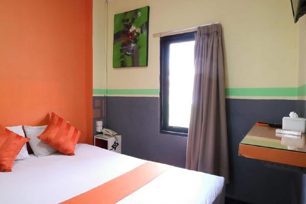 Une chambre d’hôtel avec un lit, un bureau avec un téléphone et une fenêtre avec des rideaux.