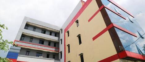 A modern building with multiple floors, large windows, and a mix of red and beige colors.