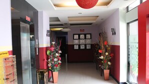 A hotel lobby with a reception desk, a phone charging station, and potted plants. - Hollywood Hotel (Jakarta)