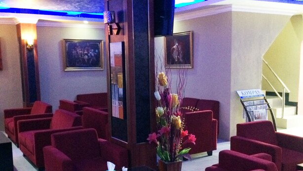 A cinema with red seating, a central pillar, and a floral arrangement. - Hollywood Hotel (Jakarta)