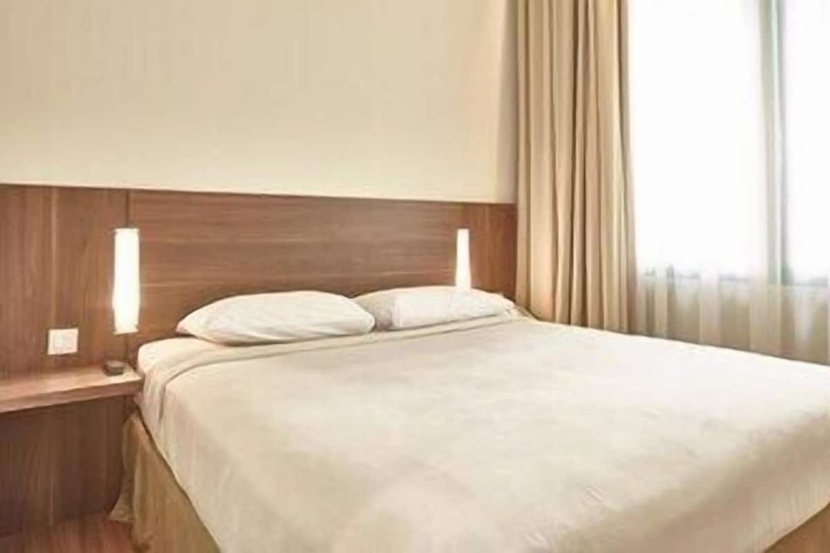Une chambre d’hôtel avec un lit, une table de chevet et une fenêtre avec des rideaux.