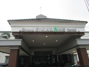 L’entrée du Grand CIKARANG Hotel, avec son toit recouvert de tuiles et une enseigne au-dessus de la porte.