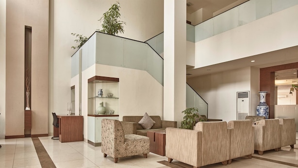 A spacious lobby with a modern staircase, seating area, and a reception desk.