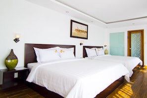 A hotel room with two beds, a painting on the wall, and a vase on the nightstand. - Melody Hotel (Xuan Huong - Da Lat)