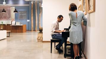 Un hall d’hôtel moderne avec un comptoir d’accueil, un piano et une femme debout près du mur.
