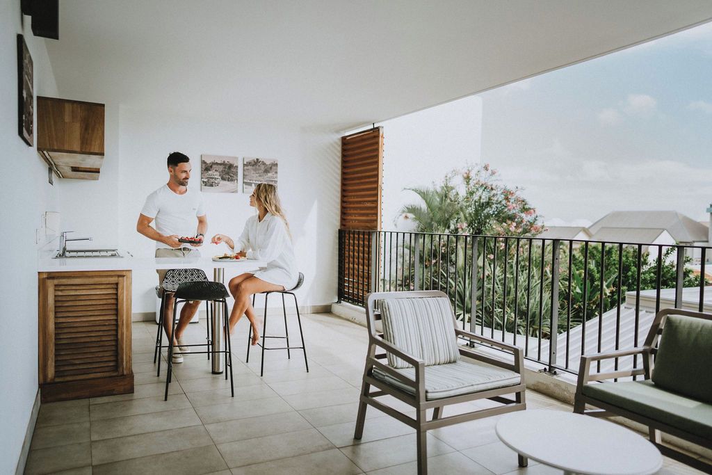 A modern kitchen with a dining area, a balcony with a view, and outdoor seating.
