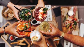 A group of people holding various drinks, likely cocktails, with garnishes and straws.