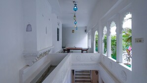 A corridor with white walls, a wooden staircase, and a dining area with a table and chairs. - Kotra Haveli A Boutique Hotel By The Lake Pichola (Udaipur)