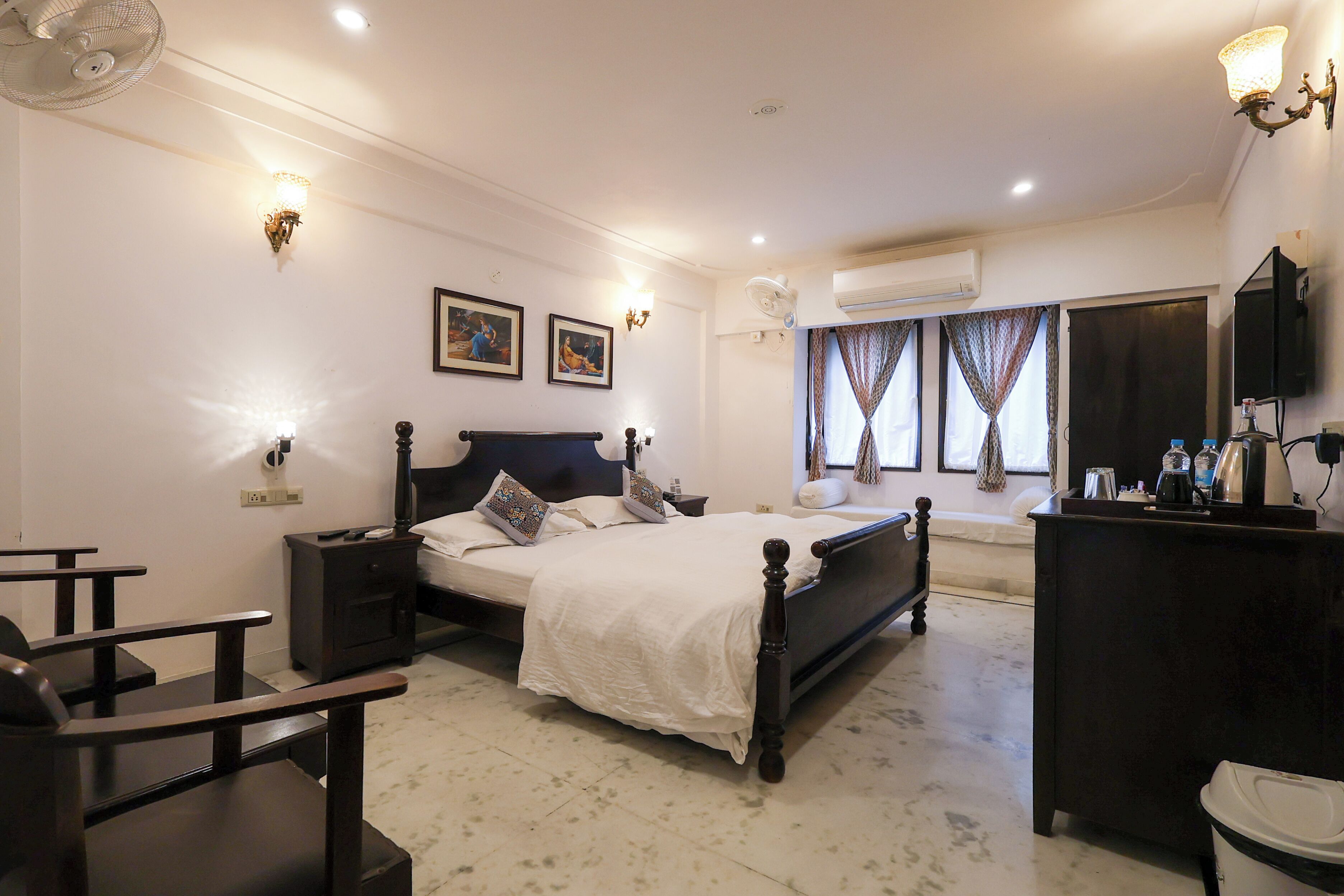 A bedroom with a bed, bedside tables, a dresser, an air conditioning unit, and wall-mounted lights.