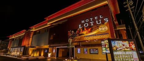Un hôtel avec une enseigne bien visible portant l’inscription « HÔTEL LOTUS » et un grand panneau d’affichage numérique.