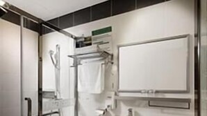 Une salle de bain moderne avec une douche à parois de verre, des toilettes blanches, un meuble-lavabo agrémenté d'une touche dorée et un grand miroir.