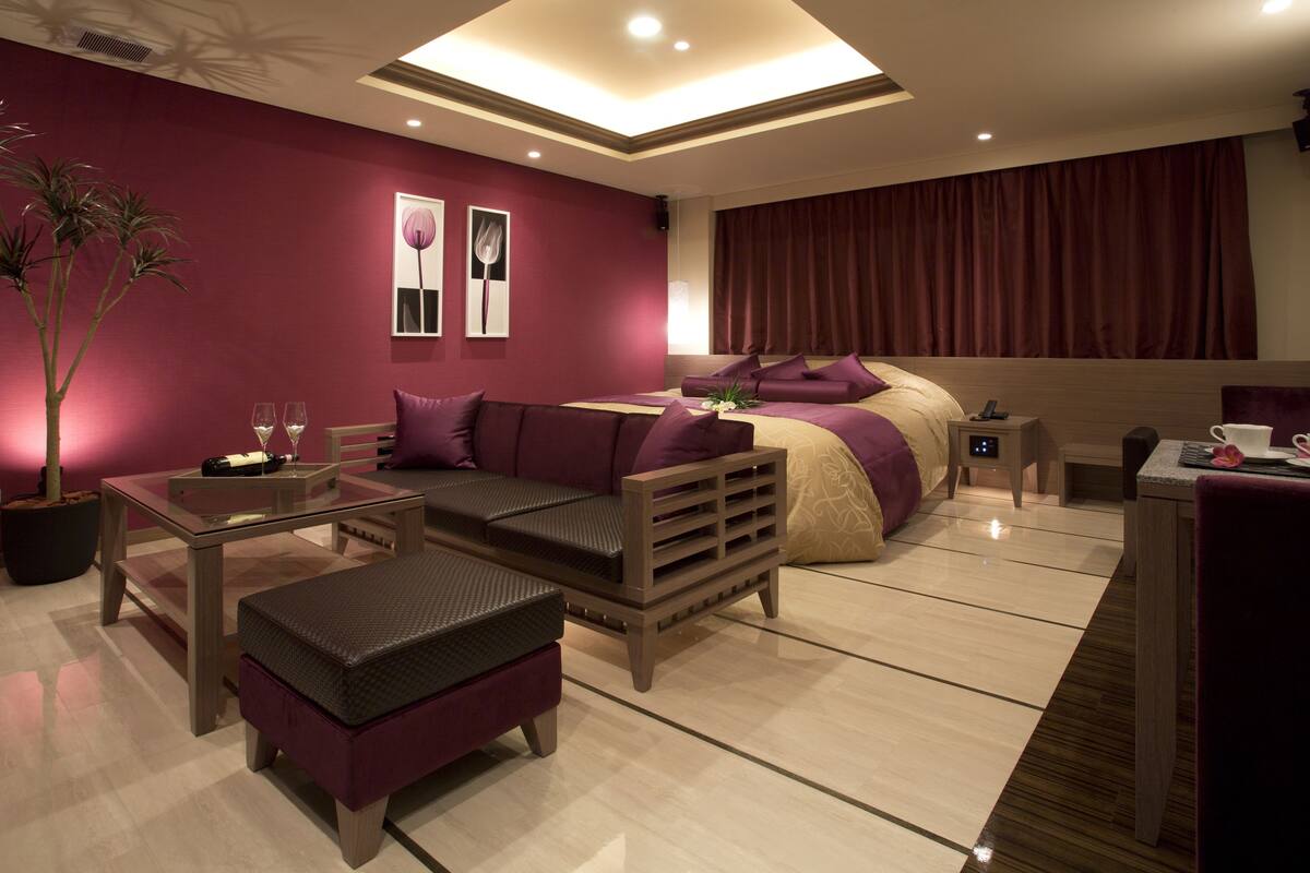 Un dormitorio moderno con una cama grande, un área de descanso con una mesa y una planta en maceta.