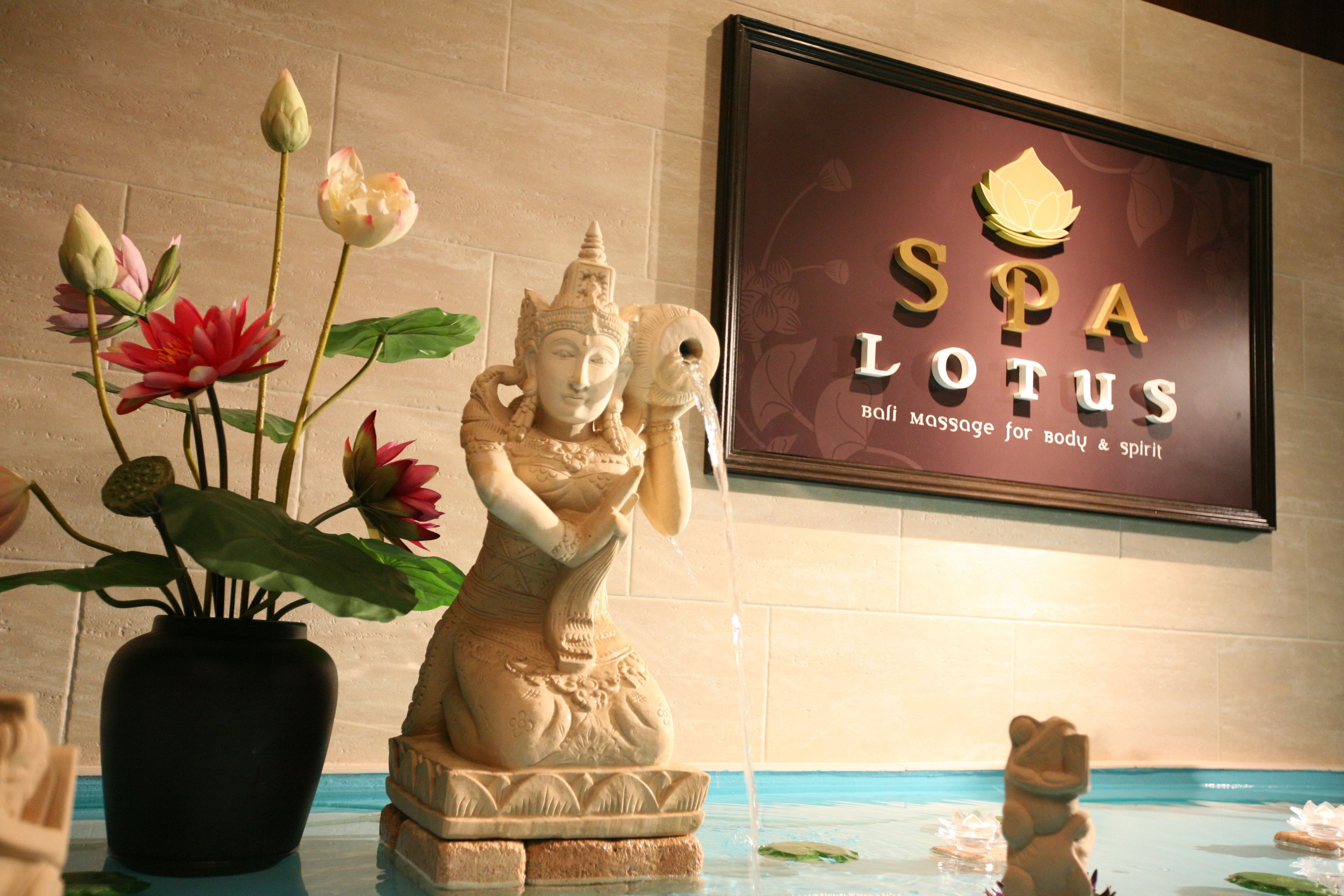 A statue of a figure holding a lotus flower, a vase with lotus flowers, and a sign for 'SPA LOTUS' with a lotus logo.