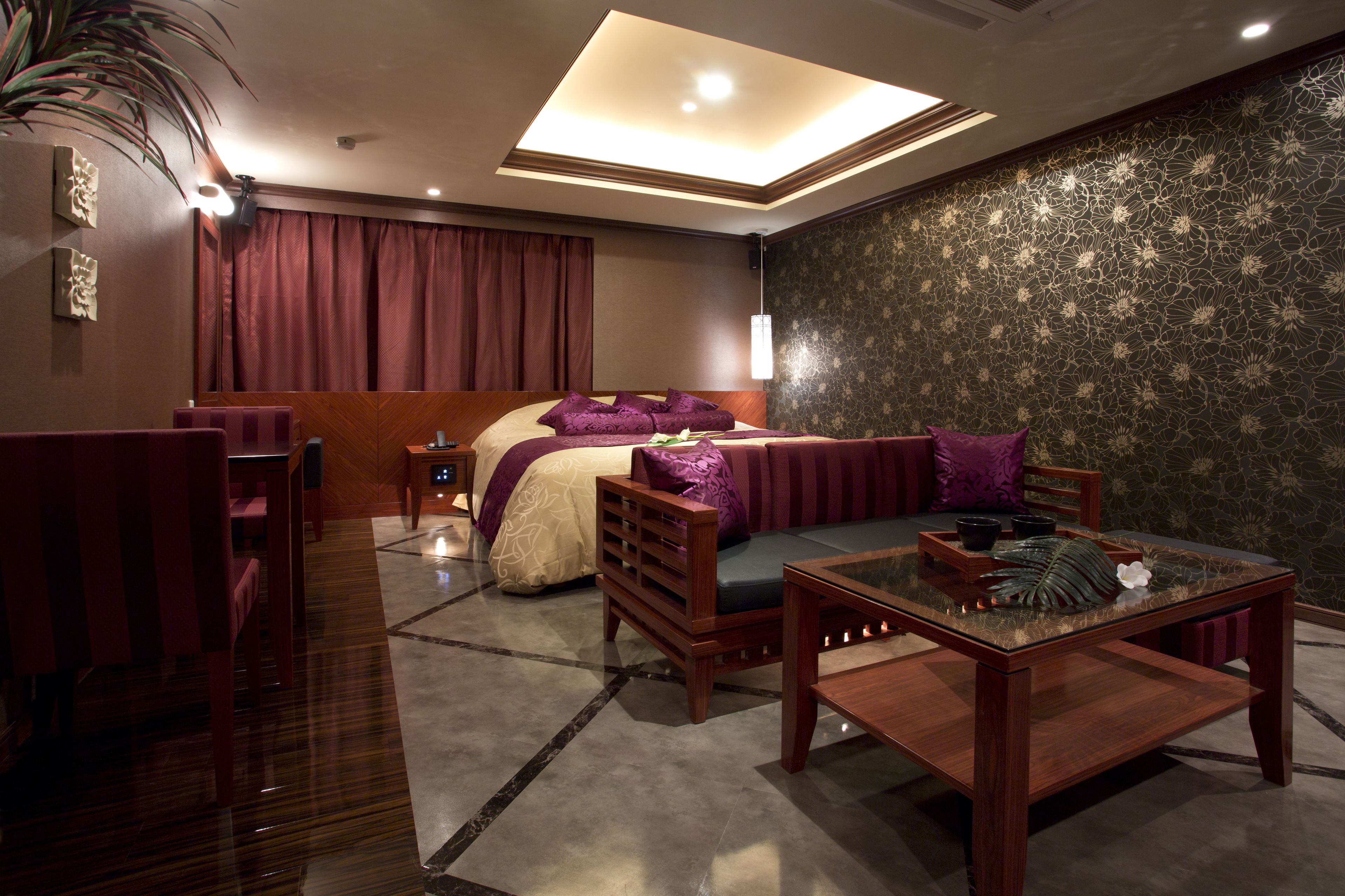 Une chambre d’hôtel avec un lit, un canapé, une table basse en bois et une petite table sur laquelle est posée une plante.