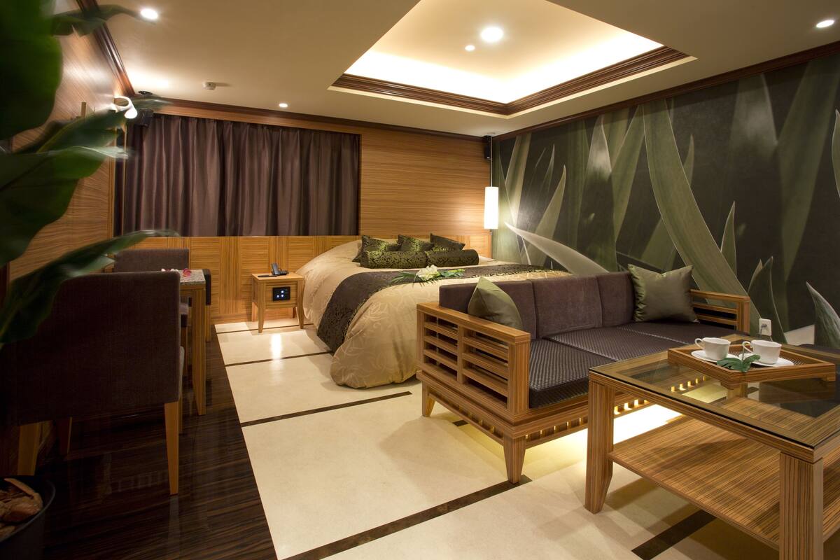 Una habitación de hotel moderna con cama, sofá, mesa de centro y escritorio.