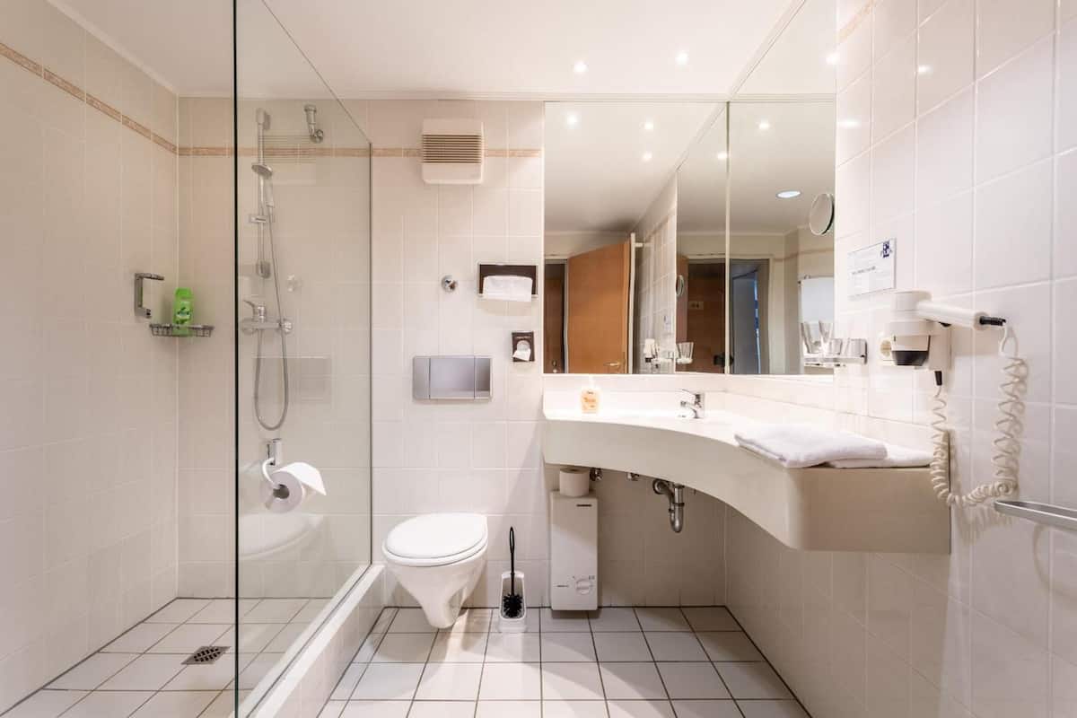 Une salle de bain moderne avec une douche à parois de verre, des toilettes, un lavabo avec un miroir et un téléphone.