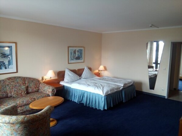 Une chambre d’hôtel avec un lit, une chaise, une petite table et deux lampes.