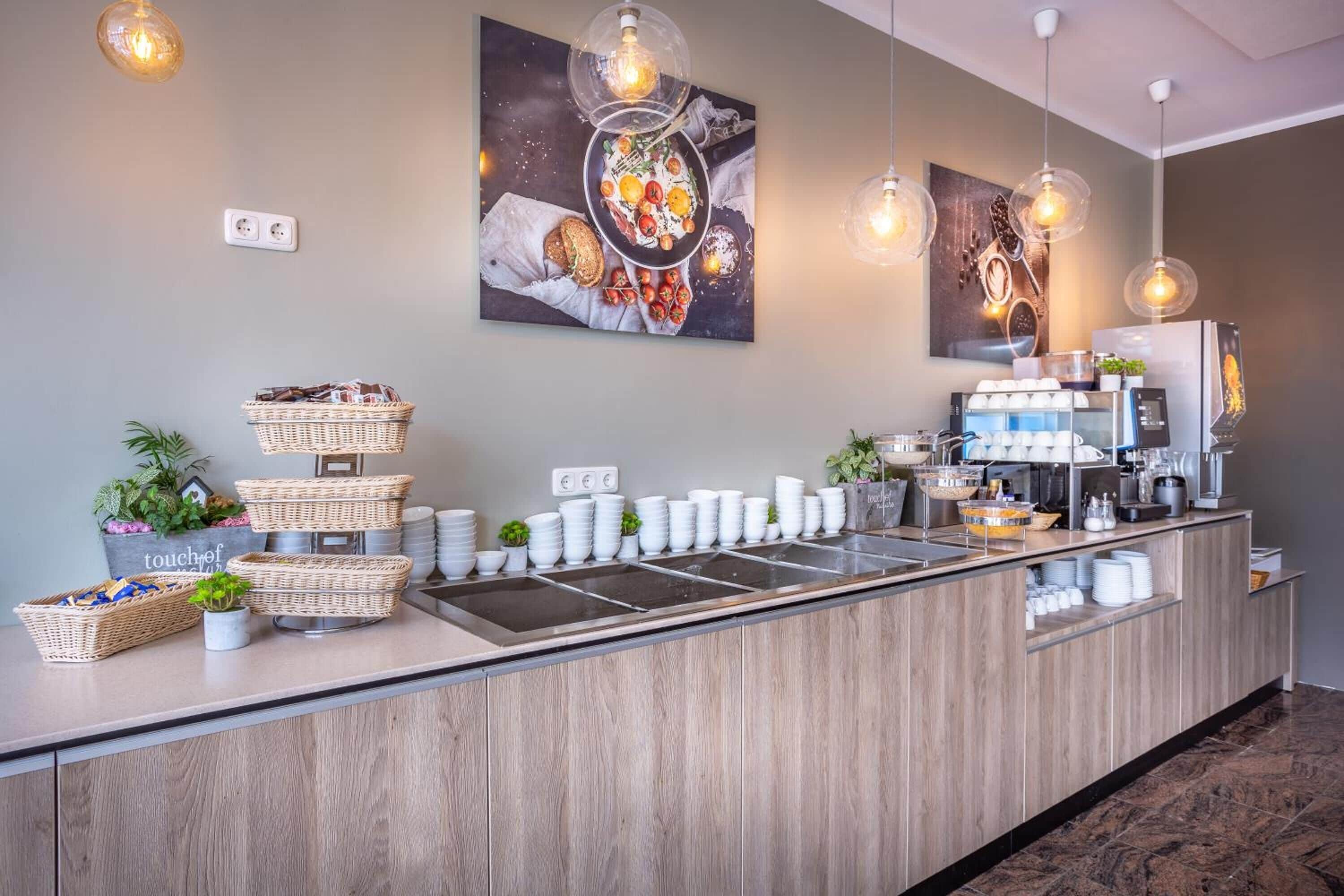A modern breakfast bar with wicker baskets, white plates, and a coffee station.