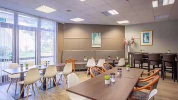 Un salón de conferencias con una larga mesa, varias sillas y un amplio ventanal.