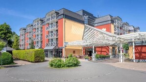 Un hôtel à plusieurs étages, doté d’une entrée couverte et d’un espace paysager agrémenté d’arbustes.