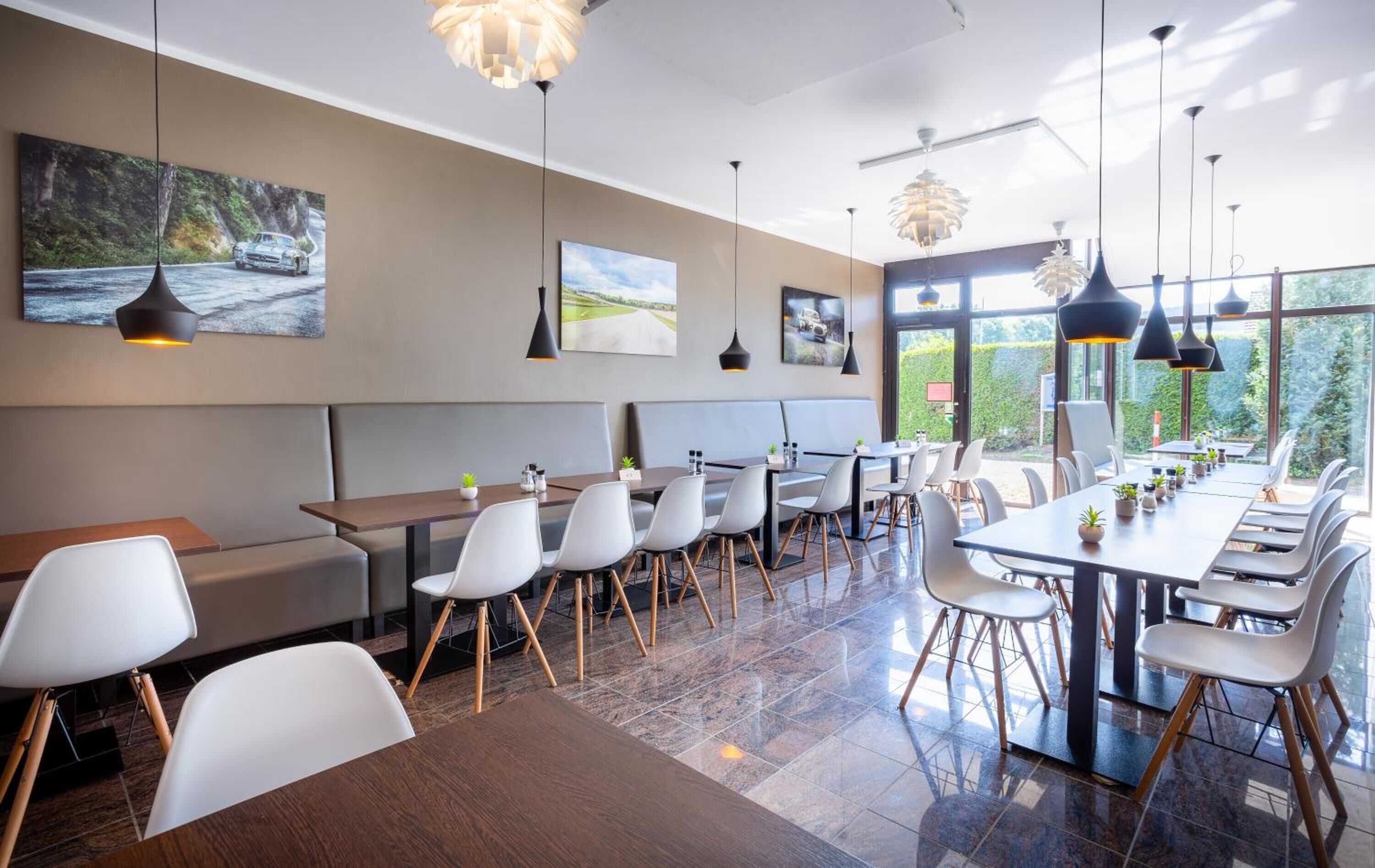 Un restaurante moderno con techos altos, ventanas amplias y una variedad de opciones de asientos, incluyendo mesas y cabinas.