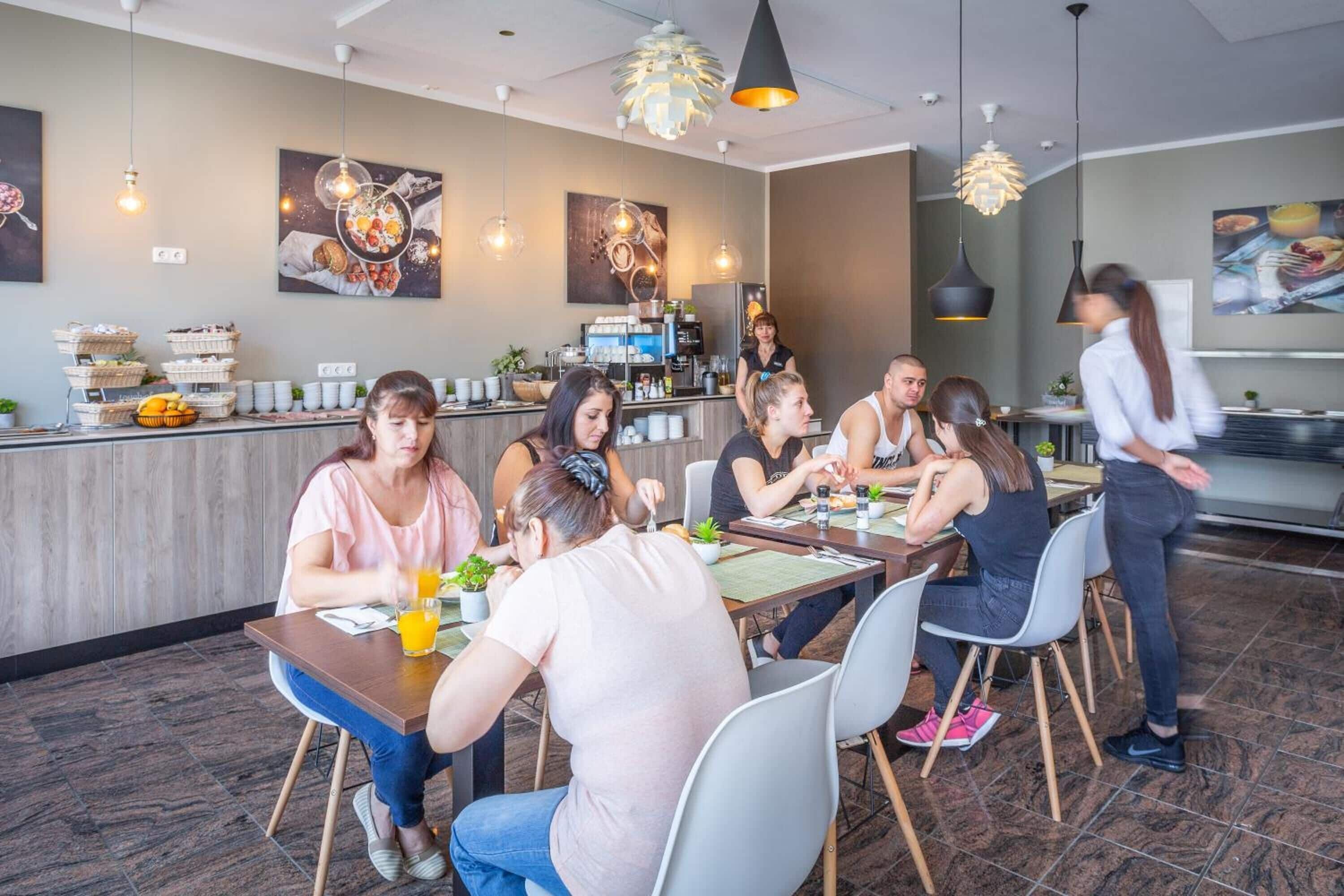 A modern restaurant interior with a bar area, dining tables, and chairs.