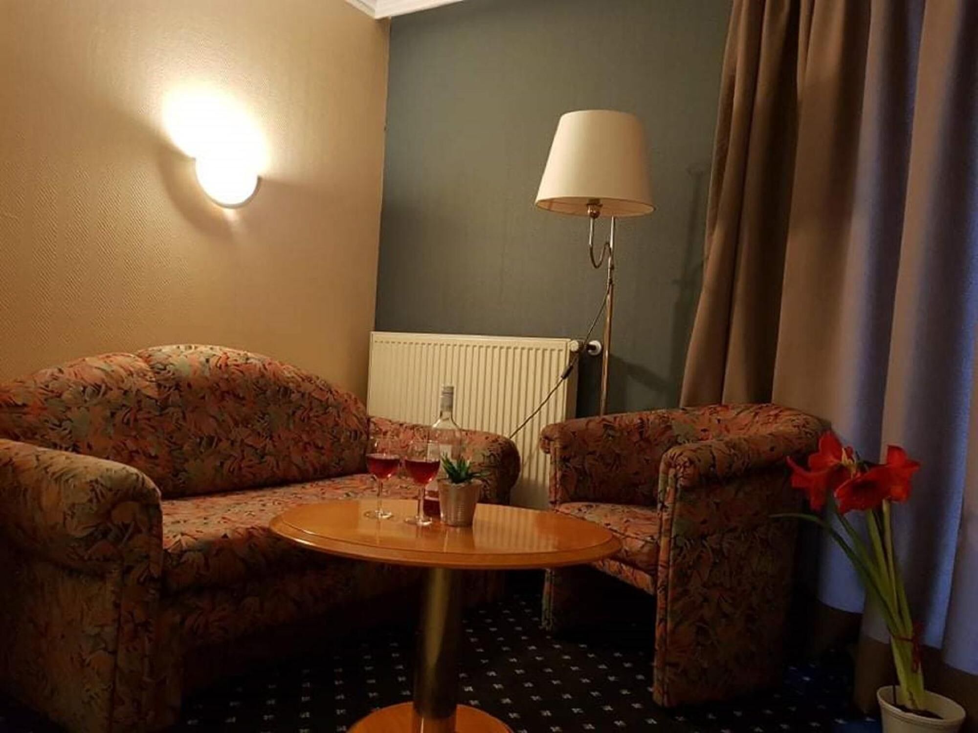 Una habitación acogedora con un conjunto de sofá, una mesita redonda, una lámpara y un radiador.