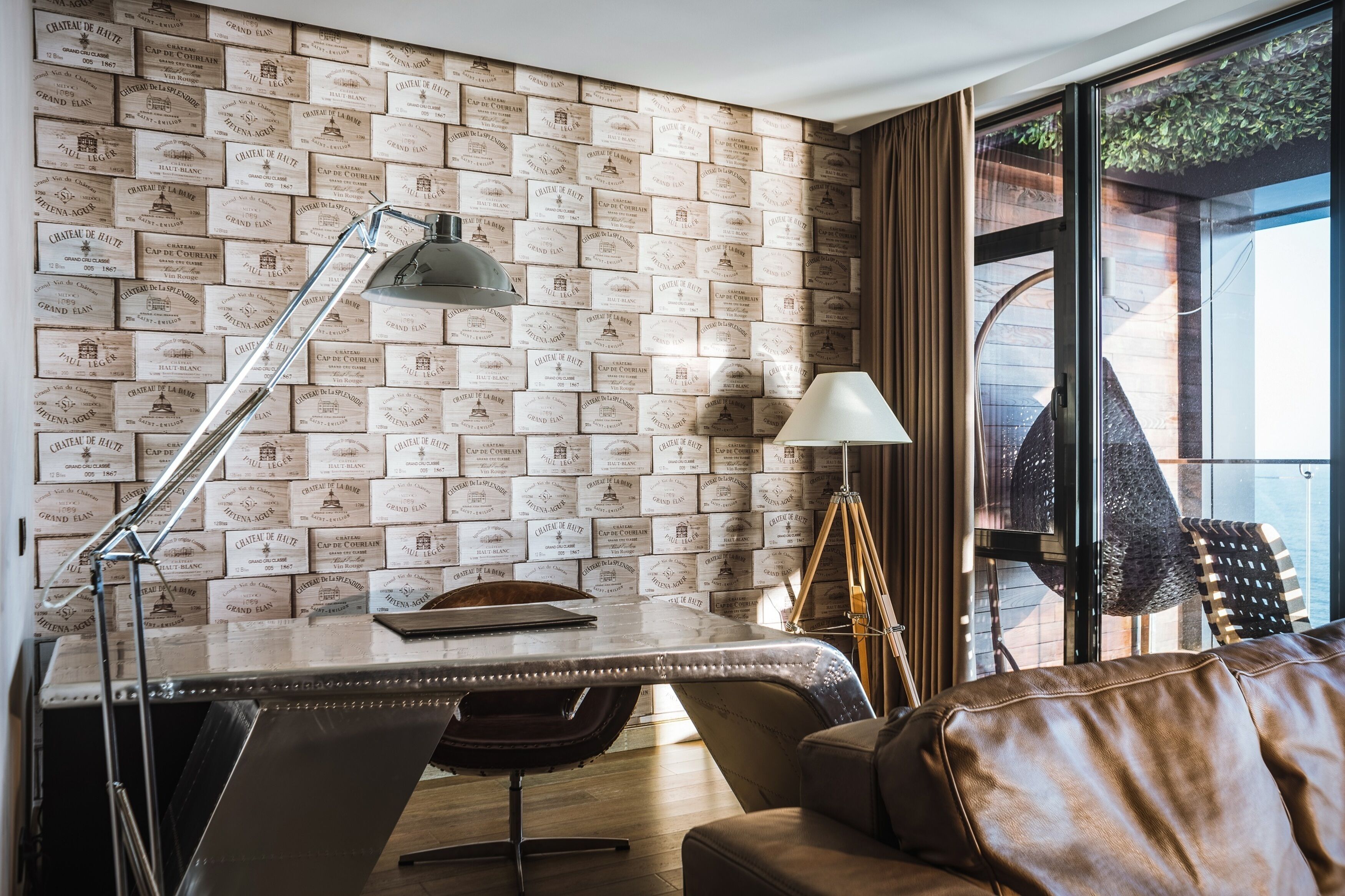 A modern room with a desk, leather sofa, and a wall covered in vintage-style tiles.