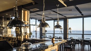 Un'area bar moderna con vista sull'oceano, con illuminazione a sospensione, un fornello e un bancone.