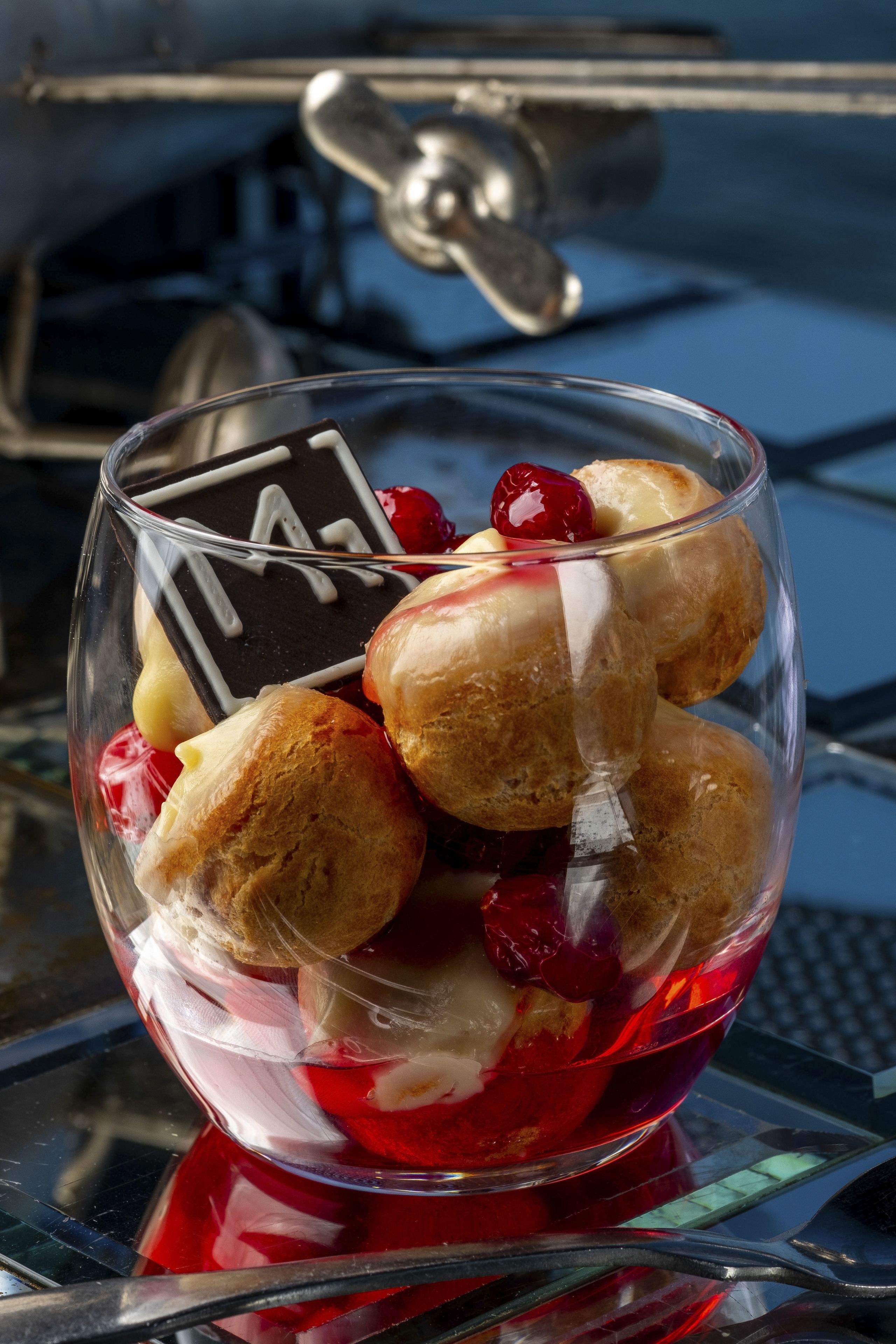A dessert in a clear glass bowl with a cherry on top.