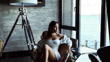 A room with a large window, a tripod lamp, and a chair.