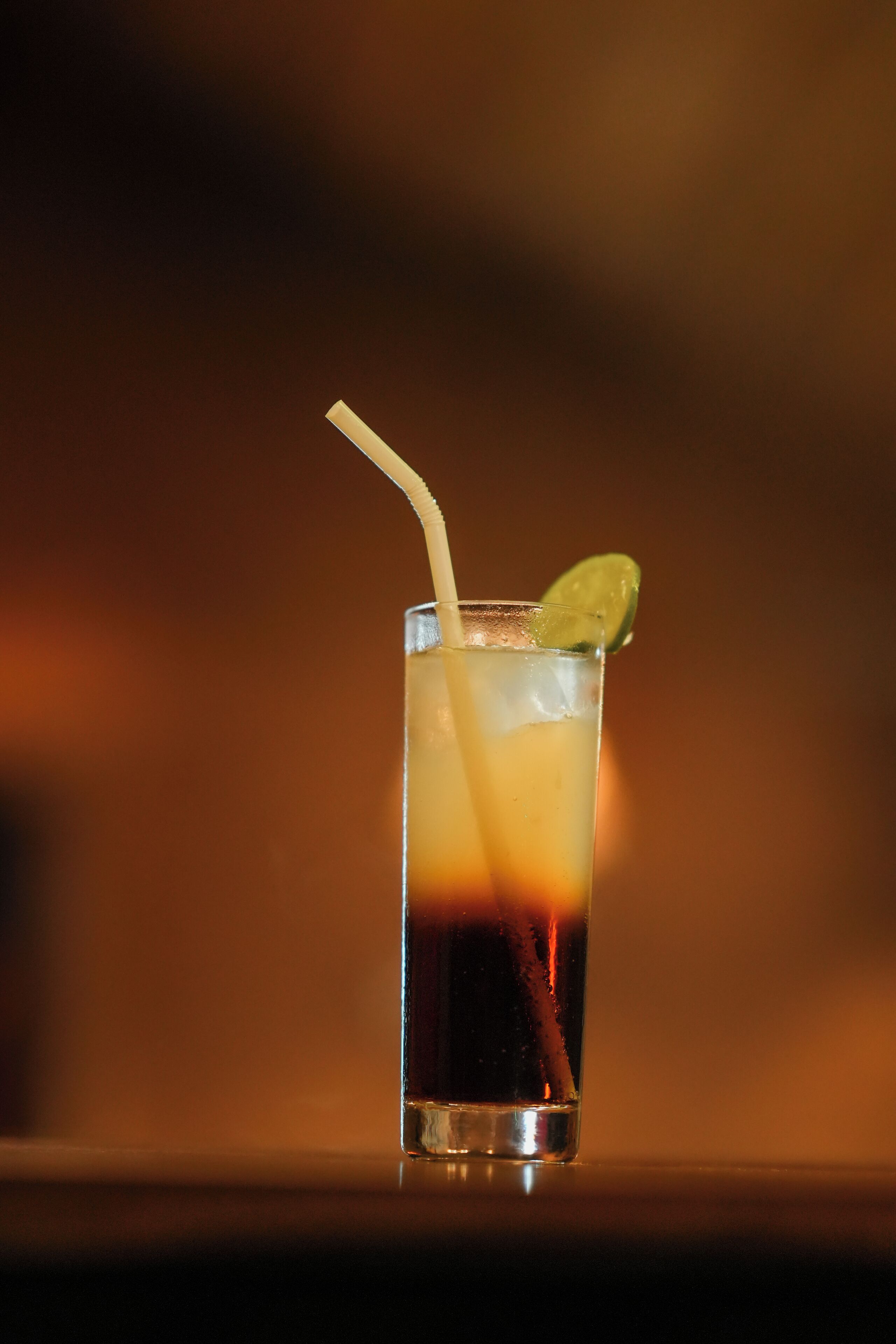 Ein Glas Eistee mit Strohhalm und Limettenspalte.