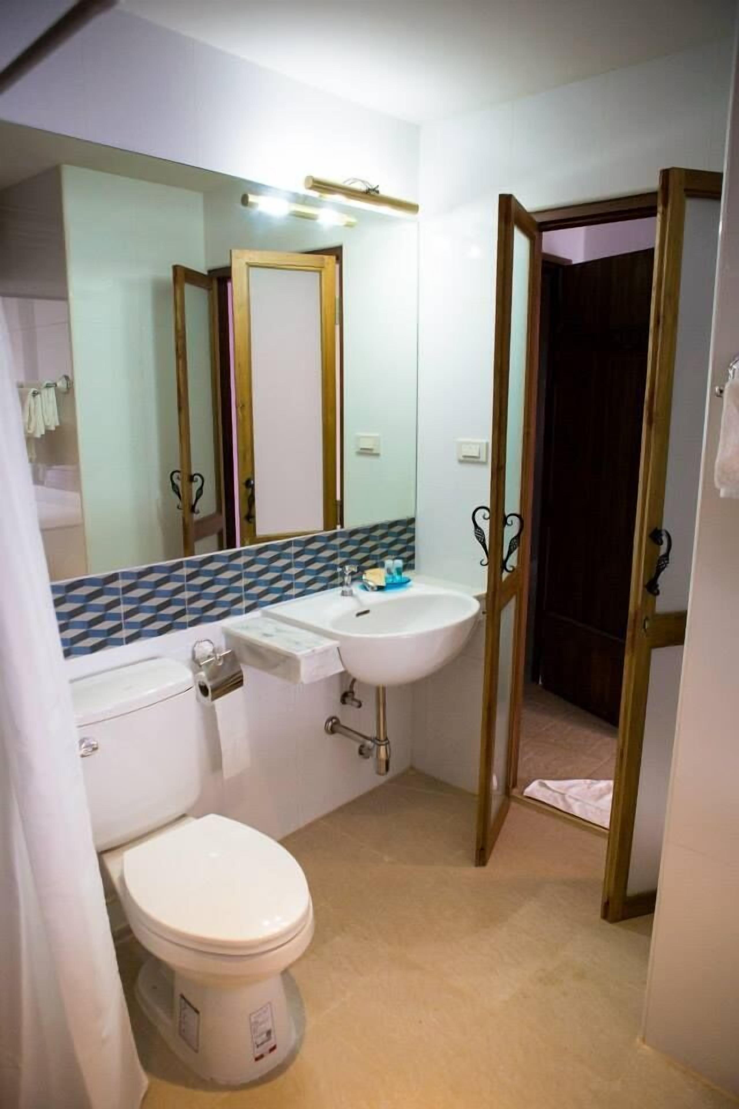 A bathroom with a toilet, sink, and mirror.