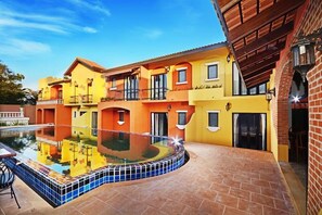 A multi-story building with a swimming pool, balconies, and a brick exterior. - Hotel Toscana Trad (Trat)