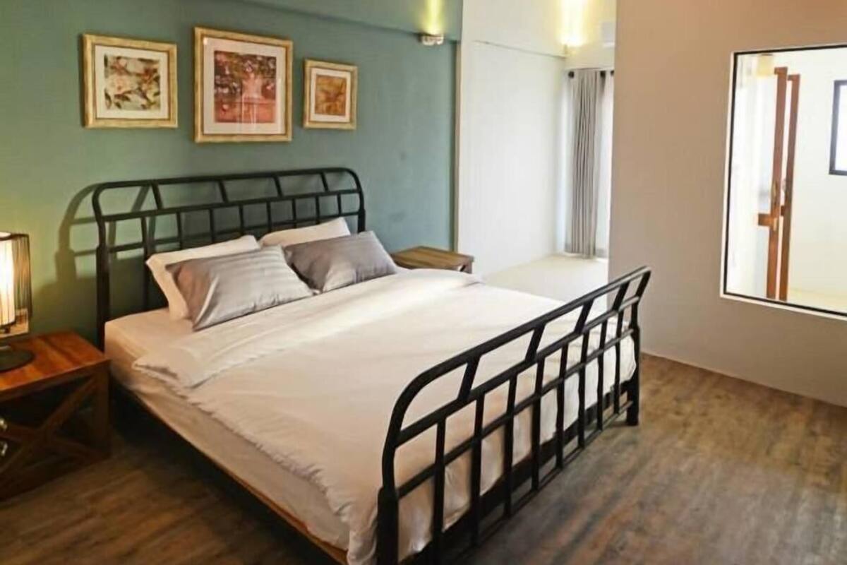 A bedroom with a bed, bedside tables, a window, and wall-mounted artwork.