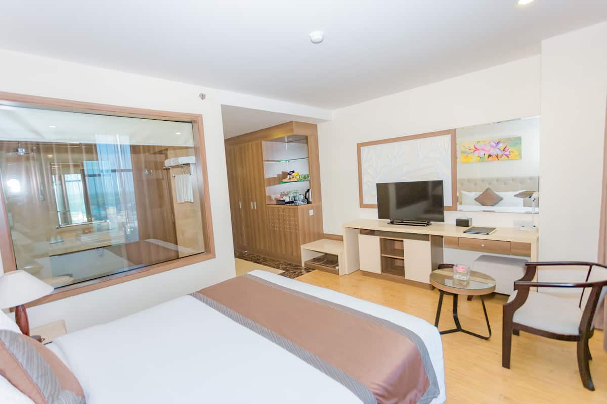 Une chambre d’hôtel avec un lit, un bureau avec une télévision, une chaise et une petite table.