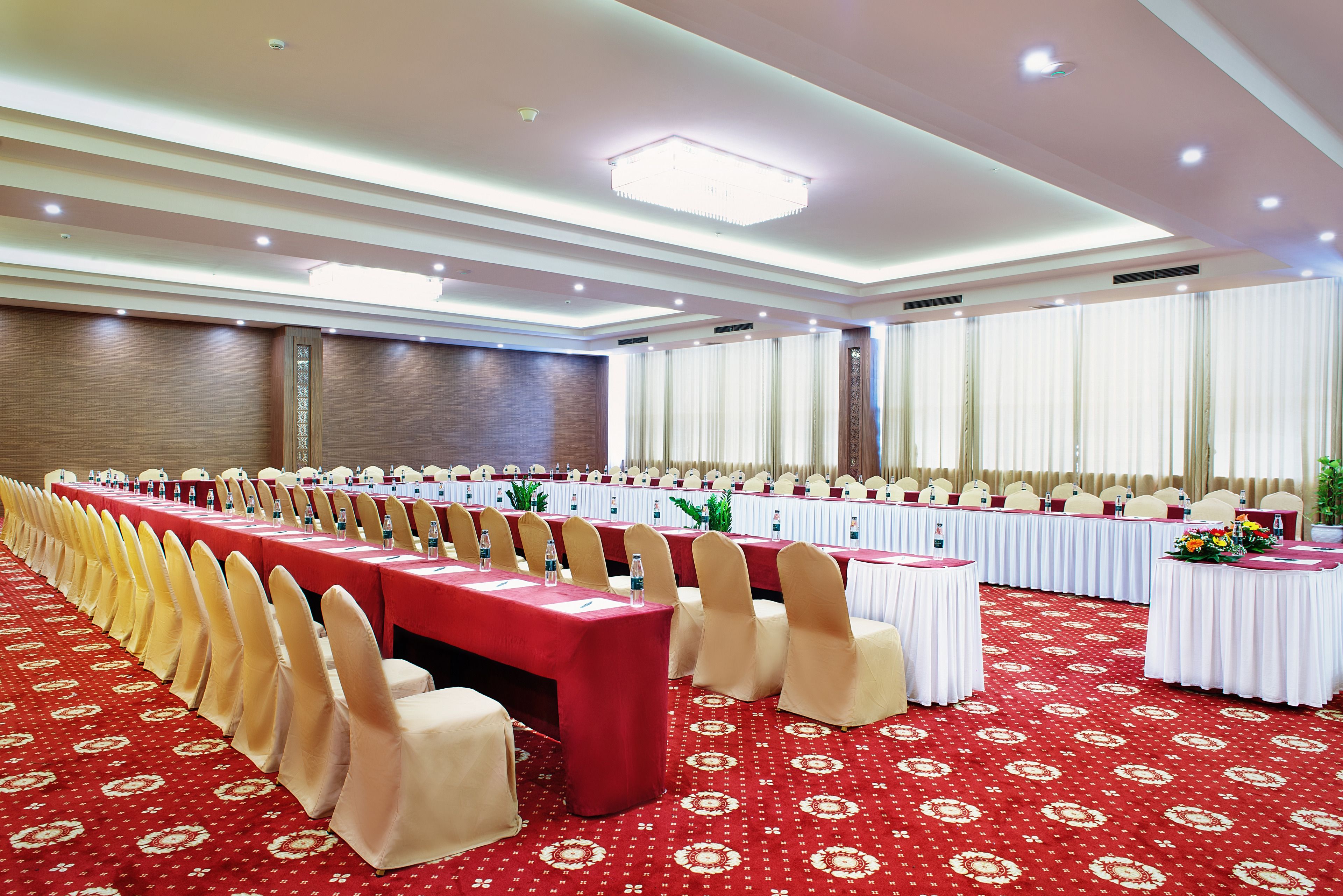 Un salón de banquetes con mesas largas, sillas y una alfombra roja.