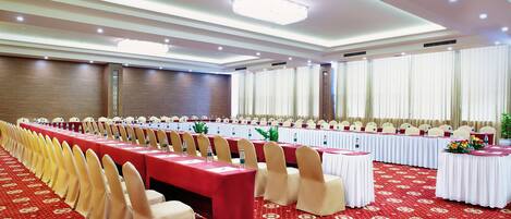 Un salón de banquetes con mesas largas, sillas y una alfombra roja.