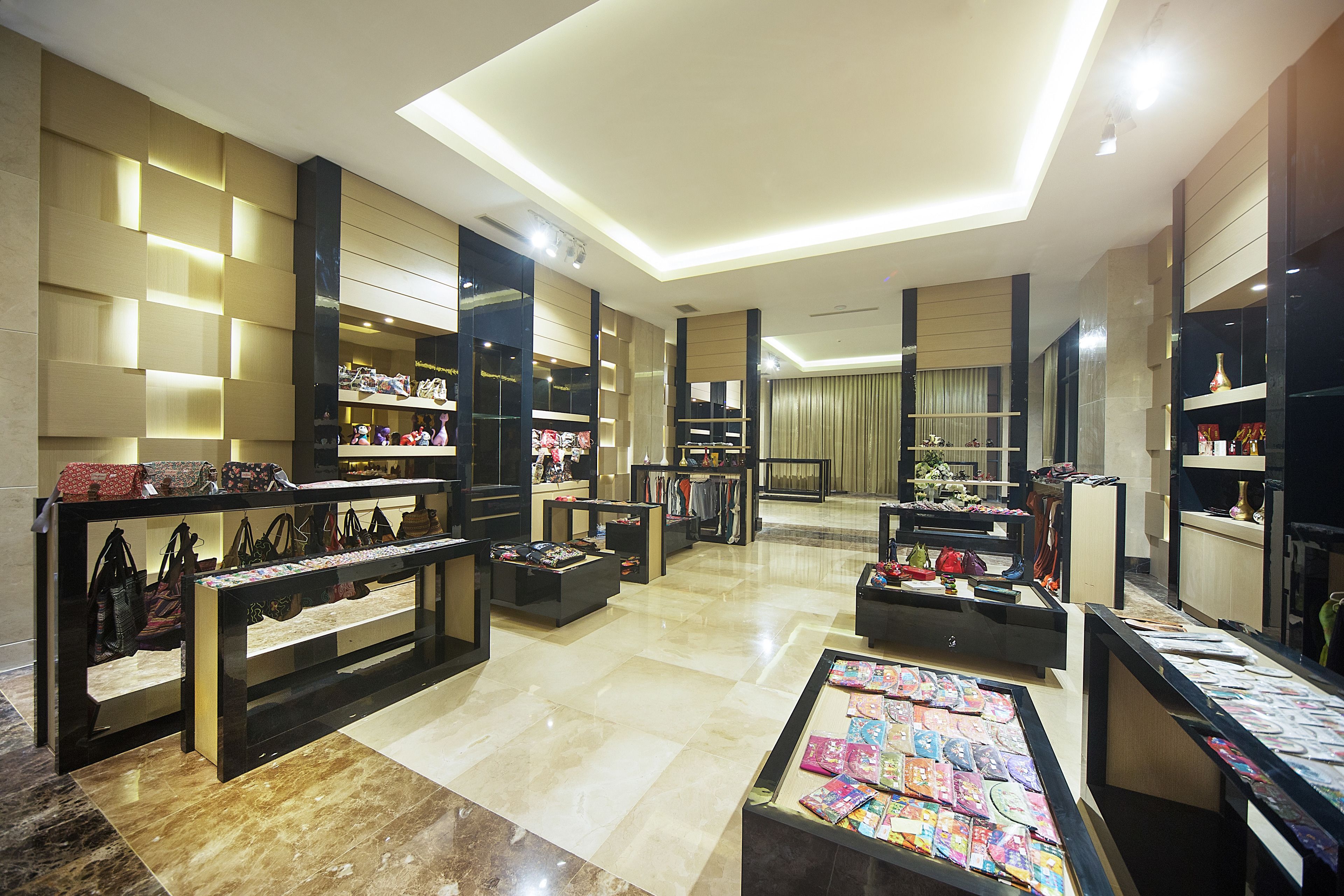 A spacious boutique hotel lobby with a modern design, featuring a central seating area, multiple display tables with items, and a well-lit ceiling.