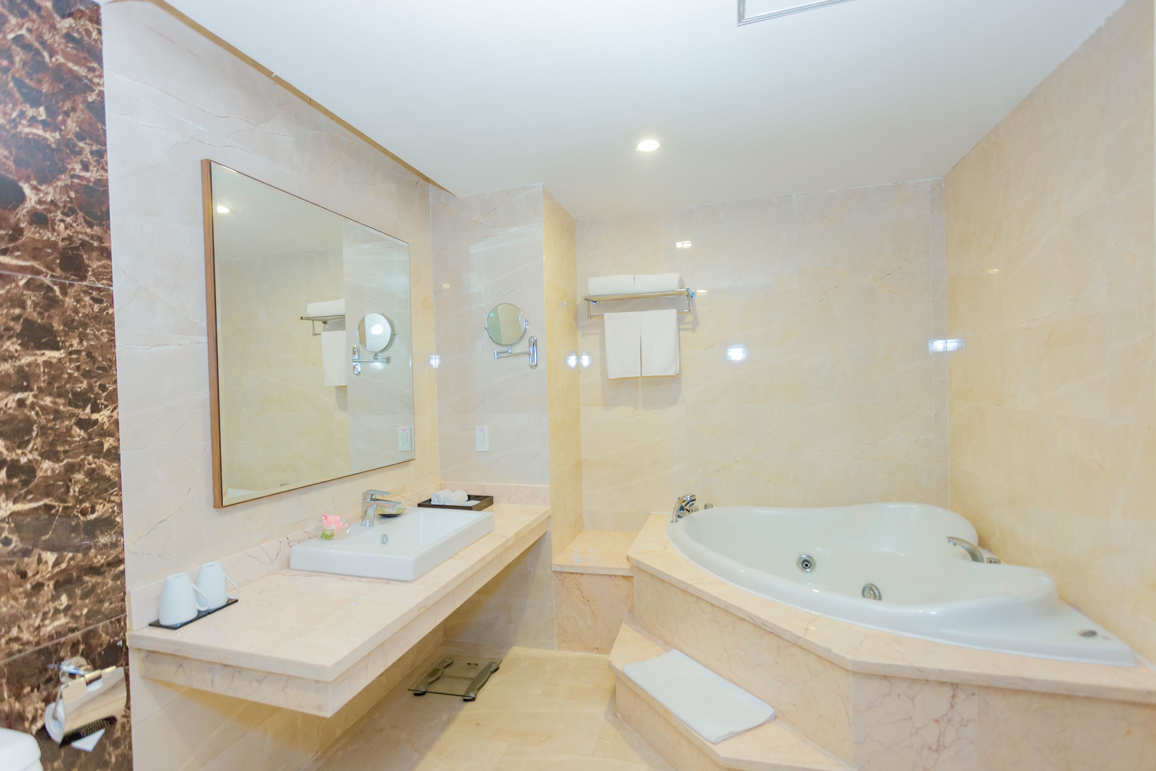 A modern bathroom with a large mirror, a sink, a bathtub, and a towel rack.