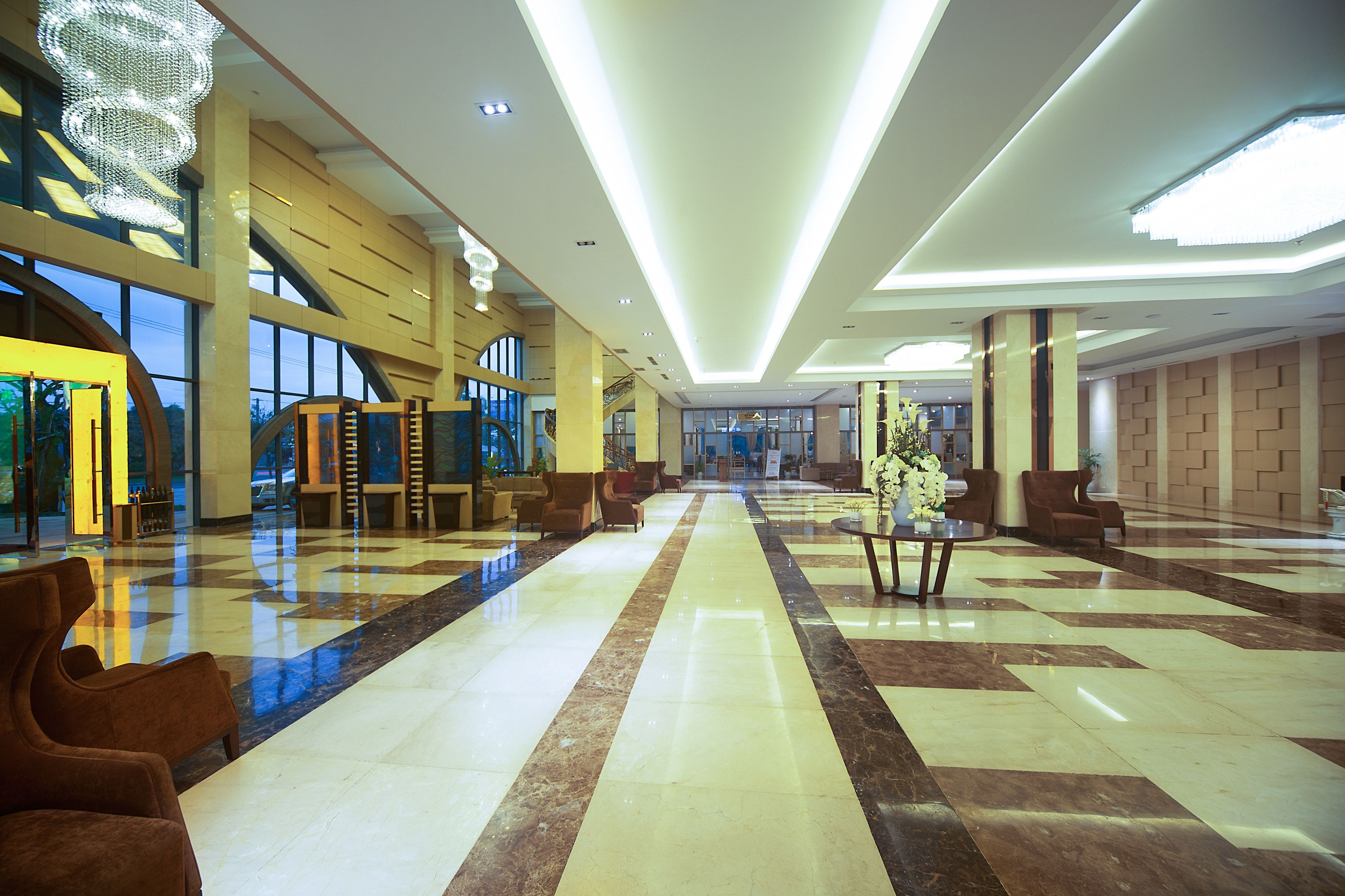 A spacious lobby with a checkered floor, seating areas, and a staircase leading to upper levels.