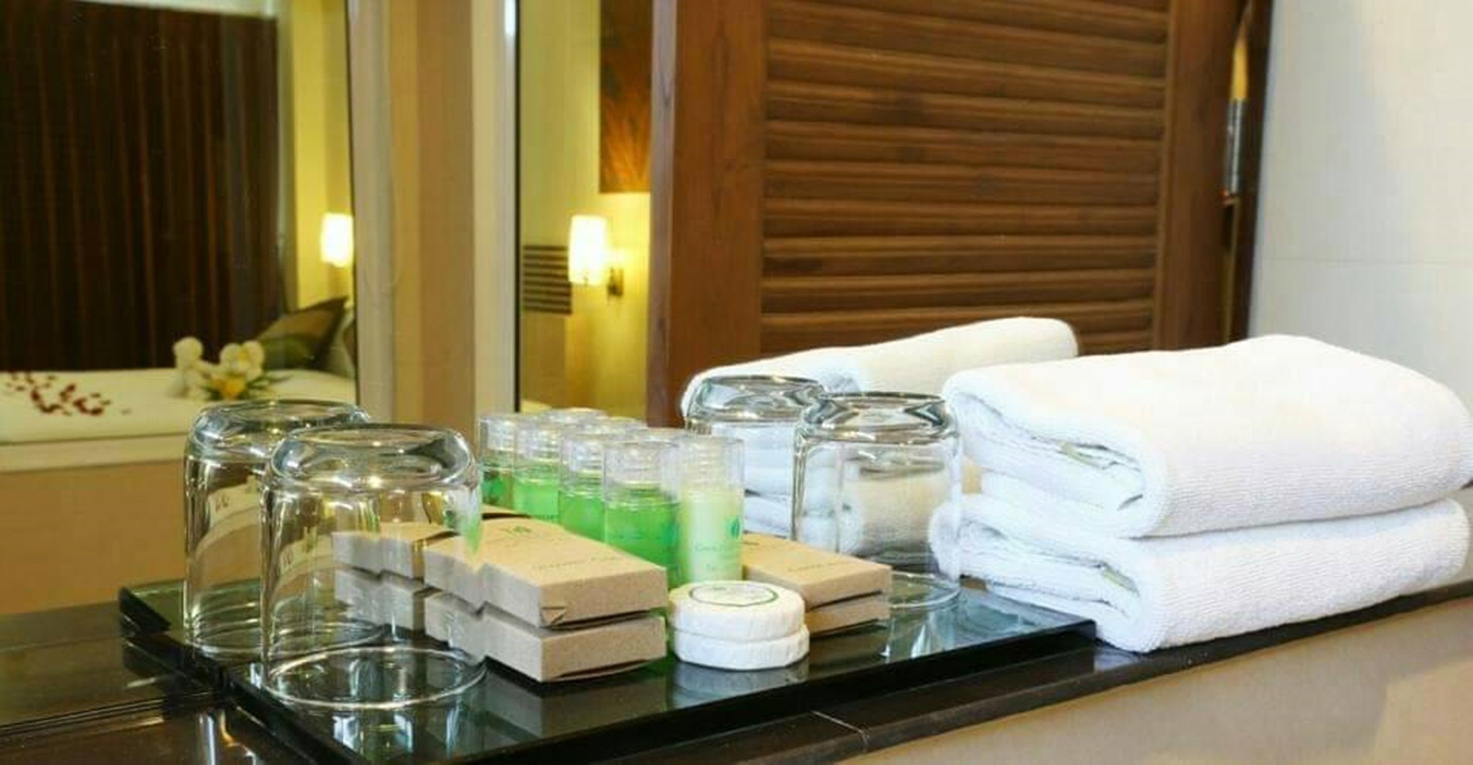 Une chambre d’hôtel avec un meuble-lavabo dans la salle de bain où sont disposés les articles de toilette et les serviettes.