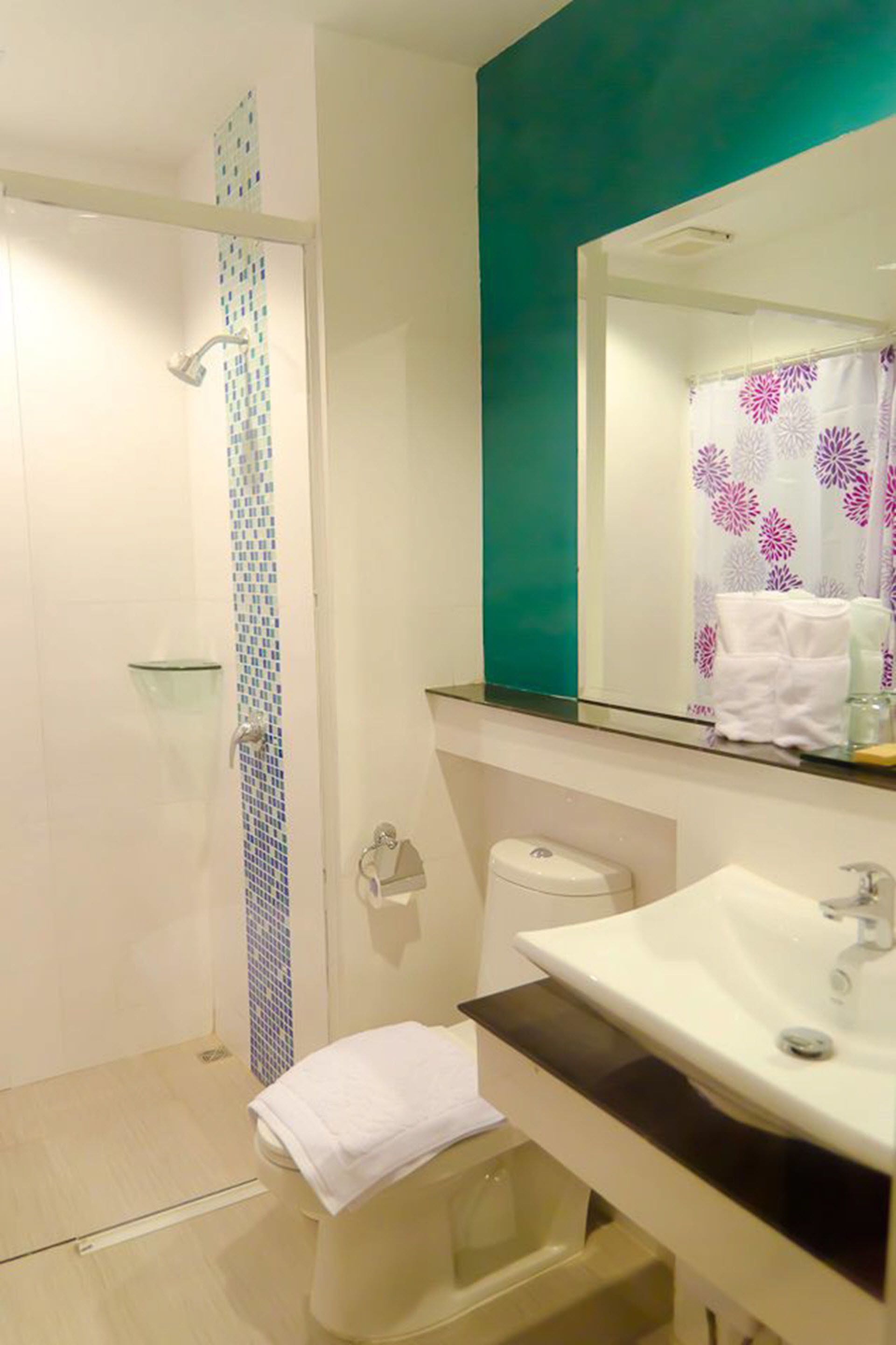 Un bagno con doccia, WC, lavandino e specchio.