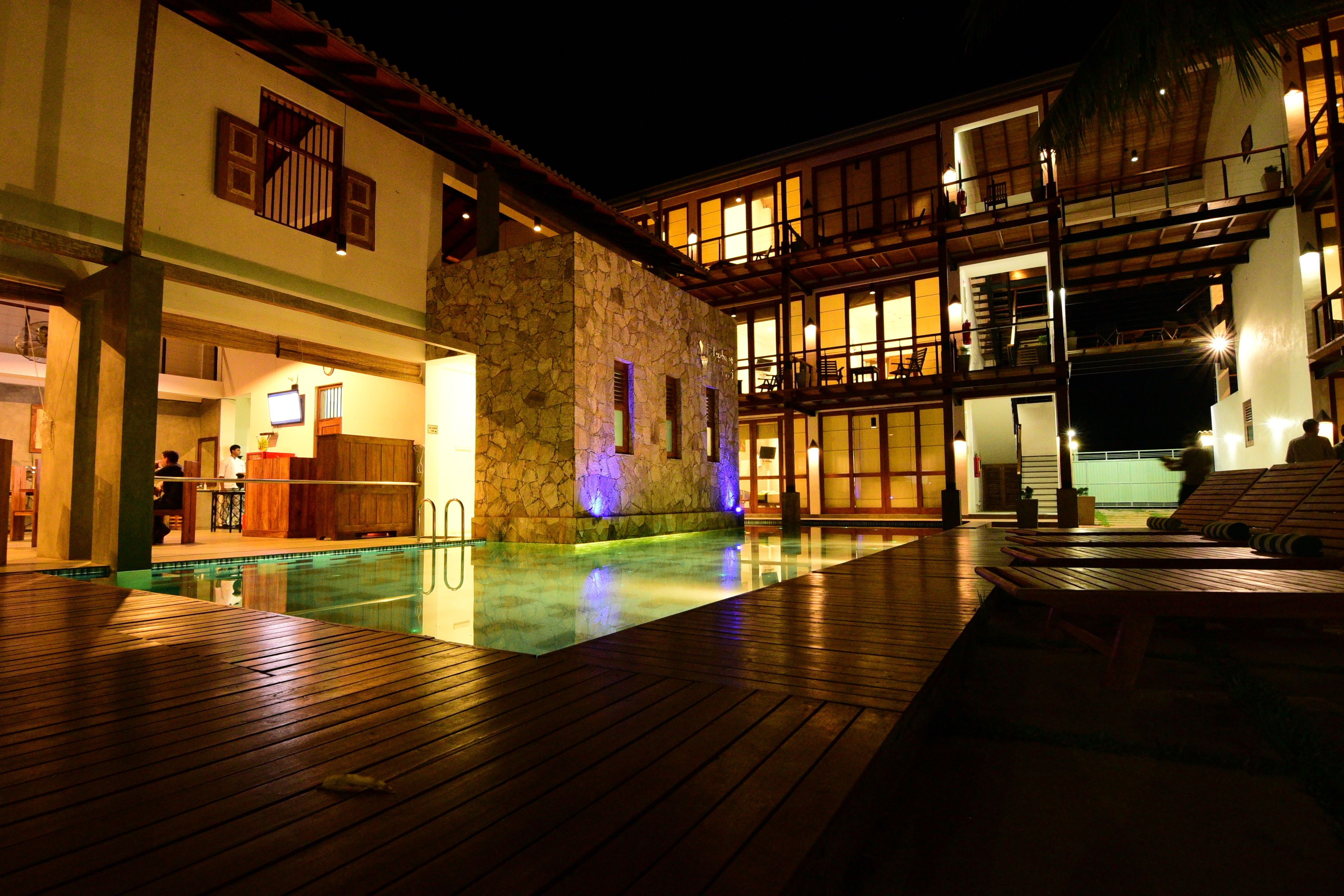 Ein Hotel mit Poolbereich, einer Stein-Fassade und mehreren Balkonen.