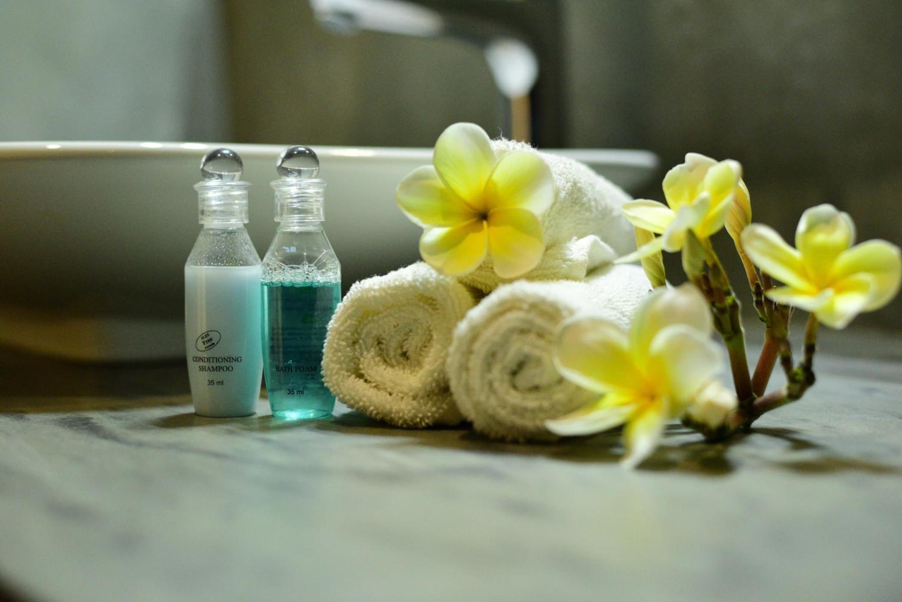 Two bottles of shampoo and a towel with flowers on a bathroom counter.