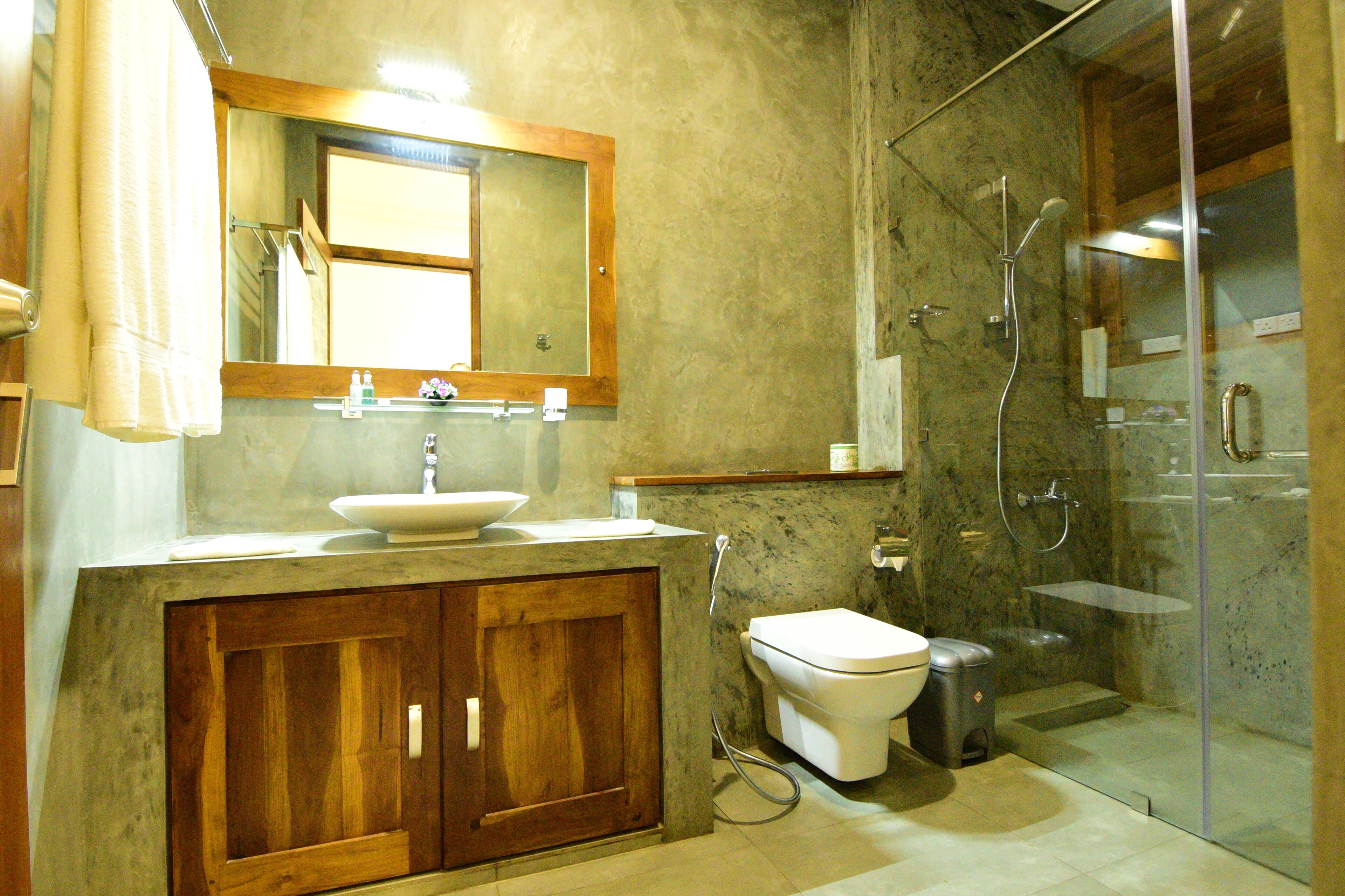 A bathroom with a wooden vanity, a sink, a toilet, and a glass-enclosed shower area.
