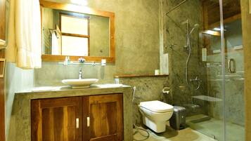 A bathroom with a wooden vanity, a sink, a toilet, and a glass-enclosed shower area.