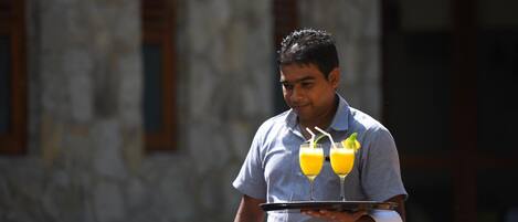 Une personne tenant un plateau sur lequel se trouvent deux verres de jus d’orange.