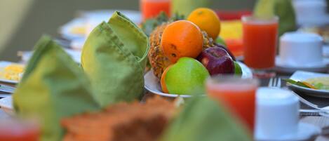 Un tavolo con diversi tipi di frutta e un bicchiere di succo.