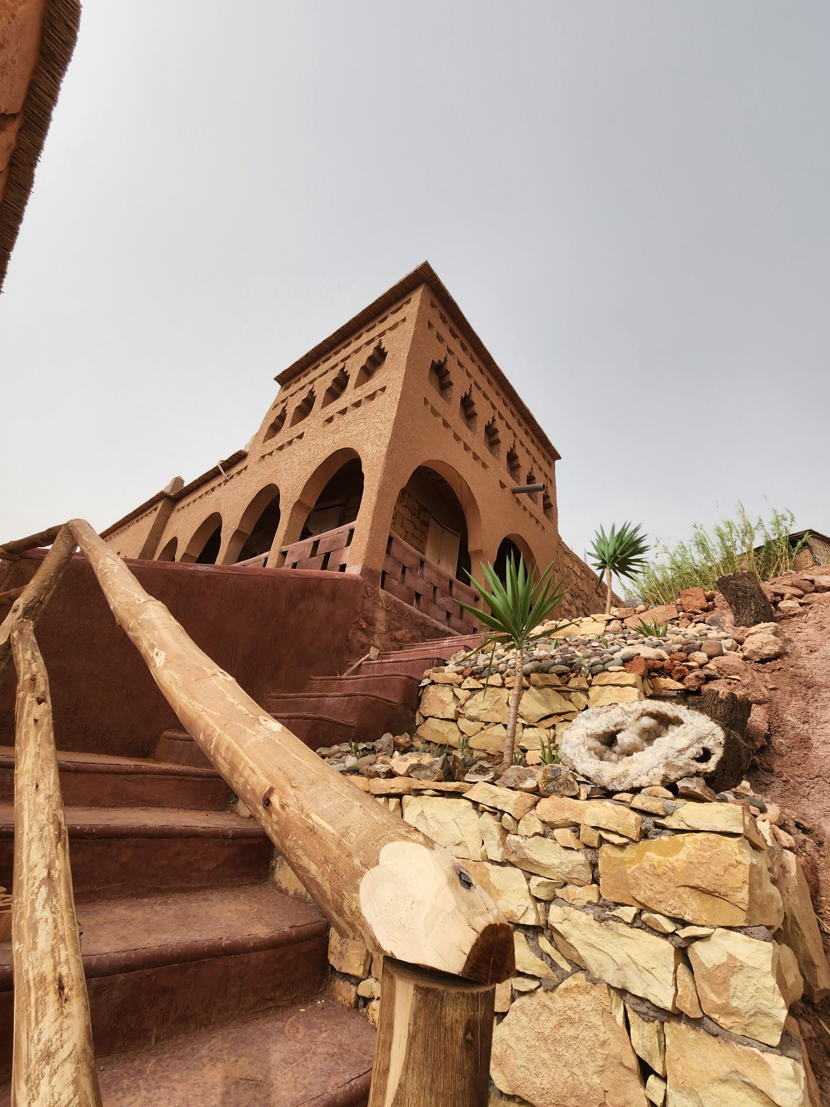 Un edificio de techo de terracota con múltiples arcos y una escalera que lo lleva hacia arriba.